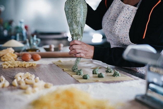 Woman preparing fresh made ravioli with ricotta cheese and spinach inside pasta factory