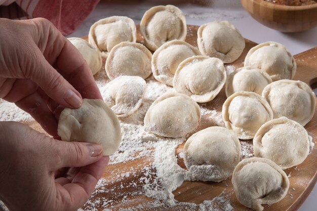 woman preparing homemade classic dumplings on wooden board