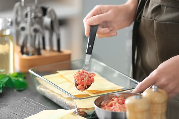 Woman preparing meat lasagna in kitchen