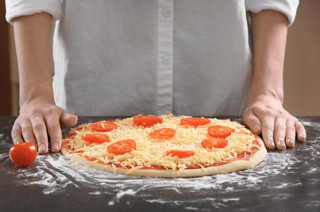 Woman preparing pizza at kitchen table