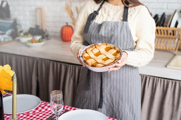 Woman preparing pumpkin pie for thanksgiving dinner at home kitchen