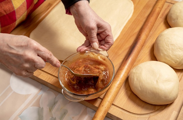 Woman preparing sweet roll cake with jam