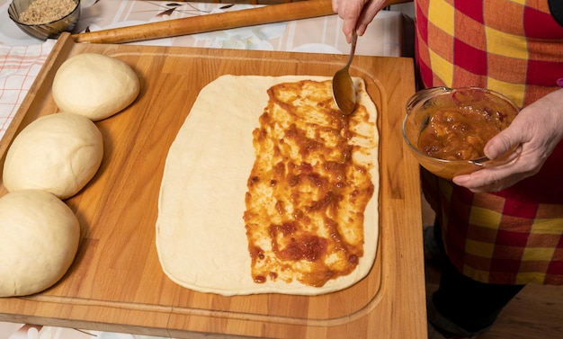 Woman preparing sweet roll cake with jam