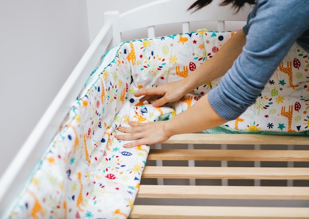 Woman preparing wooden crib for baby.