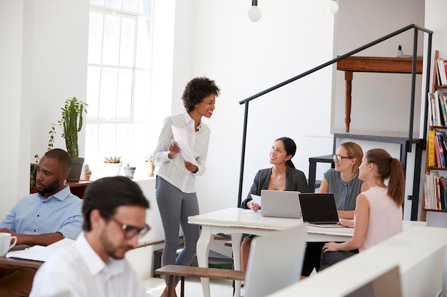 Woman presenting documents to colleagues at a desk in office