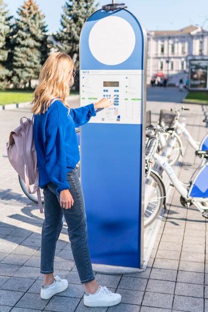 woman presses terminal buttons to rent a city bike