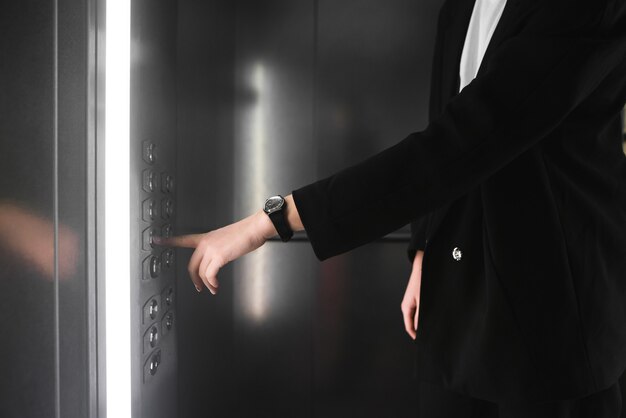 Woman pressing the button in the elevator.