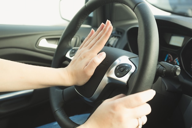 Woman pressing honk button on steering wheel