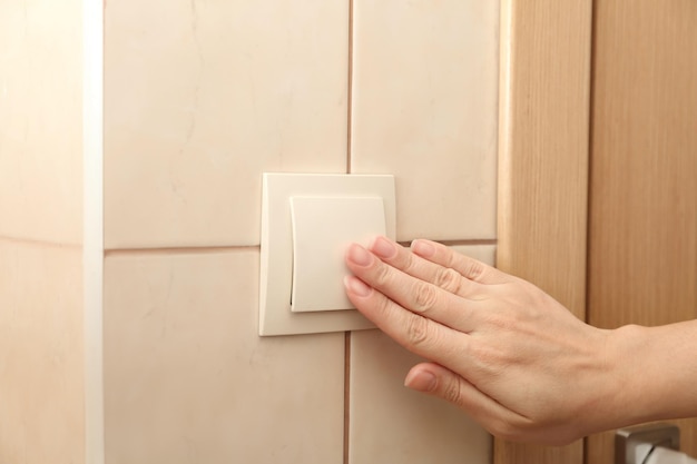 Woman pressing light switch indoors closeup of hand