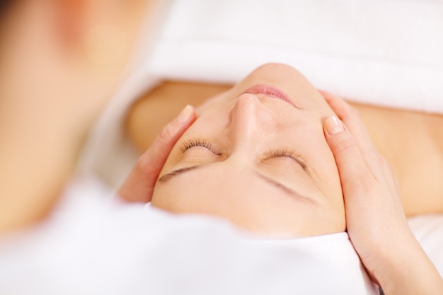 Woman under professional facial massage in beauty spa