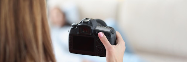 Woman professional photographer taking picture of model on sofa