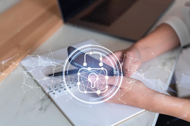 A woman programmer is browsing the Internet in smart phone to protect a cyber security from hacker attacks and save clients confidential data Padlock Hologram icons over the typing hands Formal wear