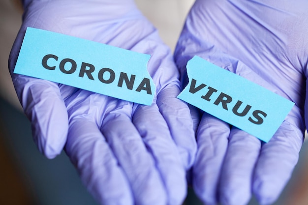 Woman in protective gloves holding inscription coronavirus