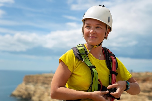 Woman in a protective helmet checks equipment and insurance before jumping off a cliff