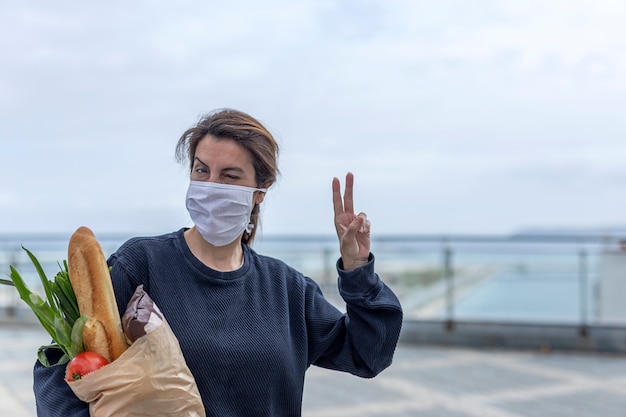 Woman in protective mask coming home with purchase