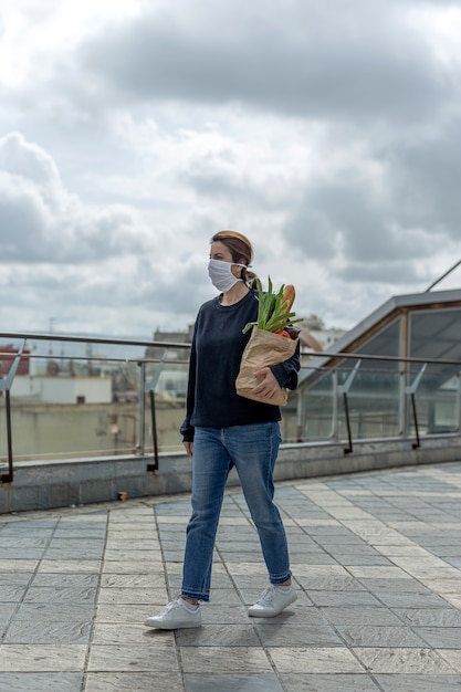 Woman in protective mask coming home with purchase