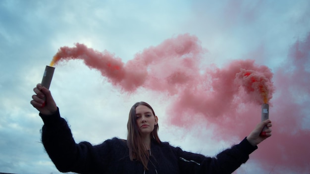 Woman protesting with smoke bombs Girl posing at camera with smoke grenades