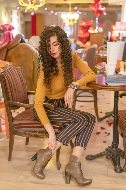 woman pulls up her shoes while sitting on a chair in a restaurant