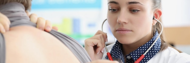 Woman pulmonologist listening to lungs of patient with stethoscope in clinic