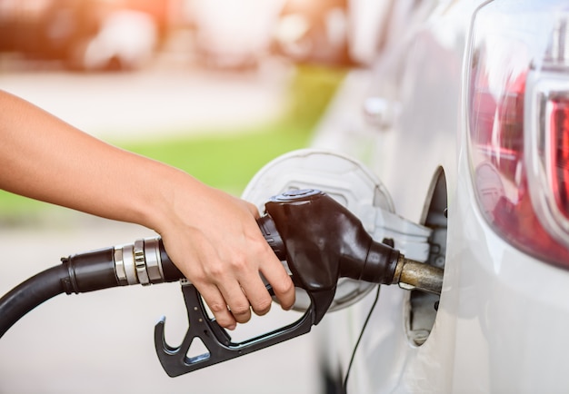  Woman pumping gasoline fuel in car at gas station