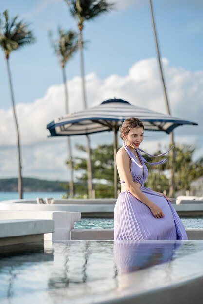 Woman in purple dress posing by the pool with sea view