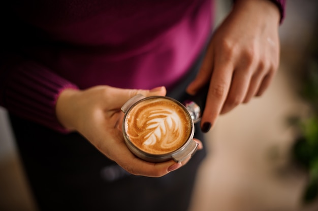 Woman in a purple shirt holding a temper with a beautiful latte art