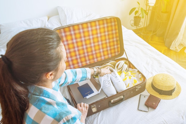 Woman put clothes in suitcase with passport laptop tickets copy space travel concept