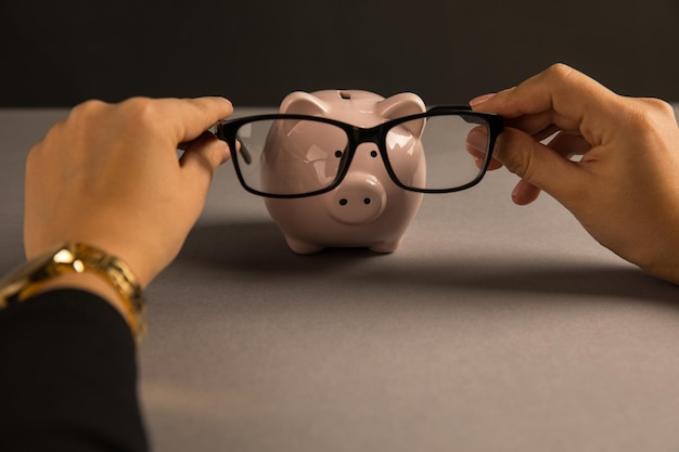 Woman put glasses on piggy bank