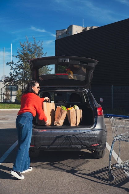 woman put packages in car trunk groceries shopping