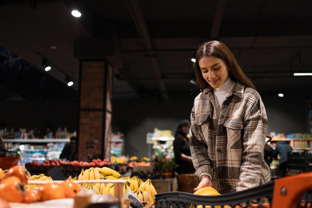 Woman puts bananas in a cart while shopping