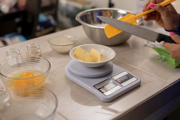 Woman putting butter on a scale to weigh and prepare bread