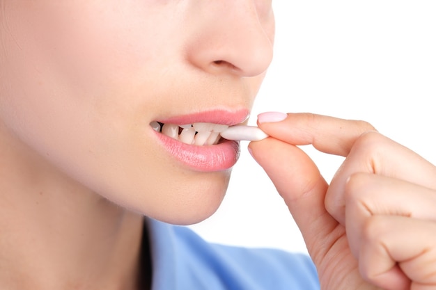 Woman putting chewing gum in her mouth with hand closeup. Protecting against caries after eating concept