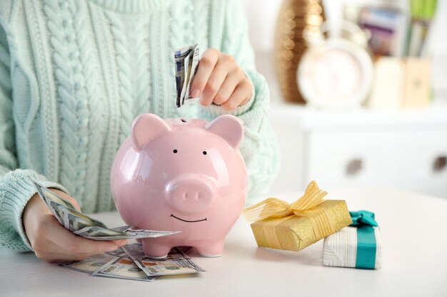 Woman putting dollar banknotes into piggy bank Savings money for gifts concept