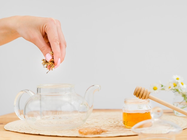 Woman putting dried herbs in teapot