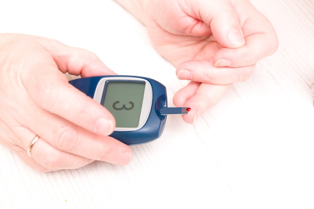 Photo woman raised a finger with a drop of blood to measure blood sugar to a glucose meter, diabetes concept