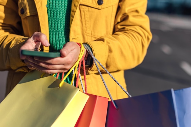 Woman raised hands up with smartphone and shopping bag with a groceries