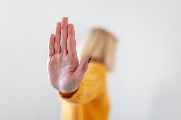 Woman raised her hand for dissuade, campaign stop violence against women. Blond woman raised her hand for dissuade with copy space