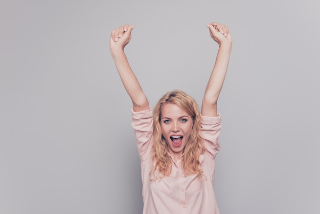 Woman raising hands up celebrating goal achievement isolated over grey