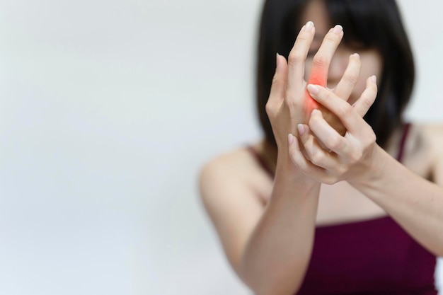 Woman raising her hand and holding her finger due to pain from rheumatoid arthritis.