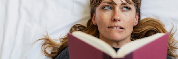 Woman reading a book on a bed during coronavirus quarantine