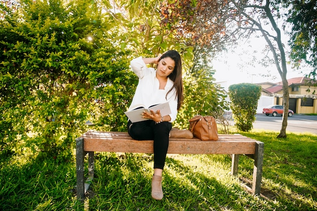 Woman reading a book in a bench of the park