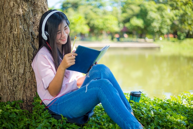 woman reading a book in the parkBeautiful young woman sitting in autumn leaves under tree