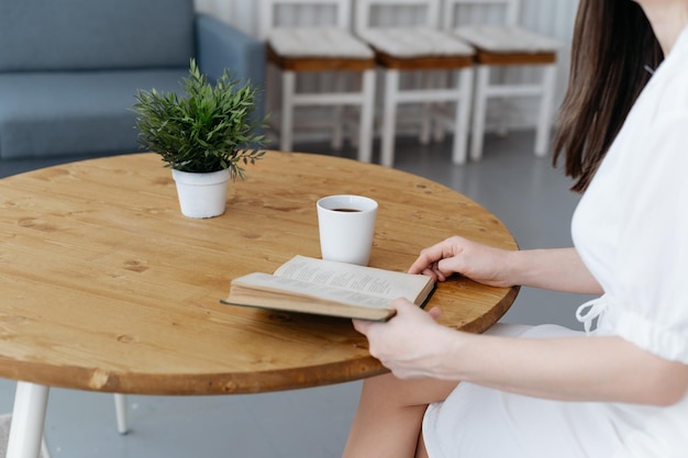 Woman reading a book sitting at a coffee table