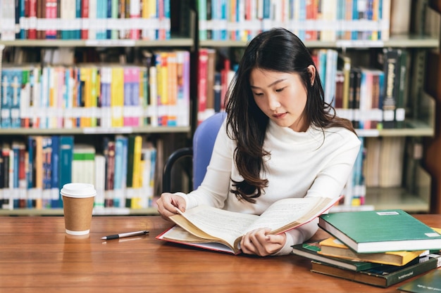 Woman reading book on table in library