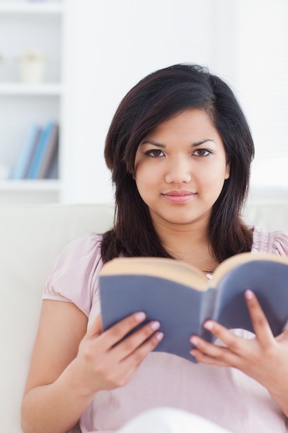 Woman reading a book while she sits on a couch