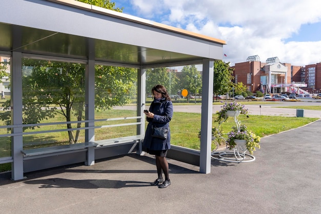 Woman reads information on a mobile phone while waiting for a bus