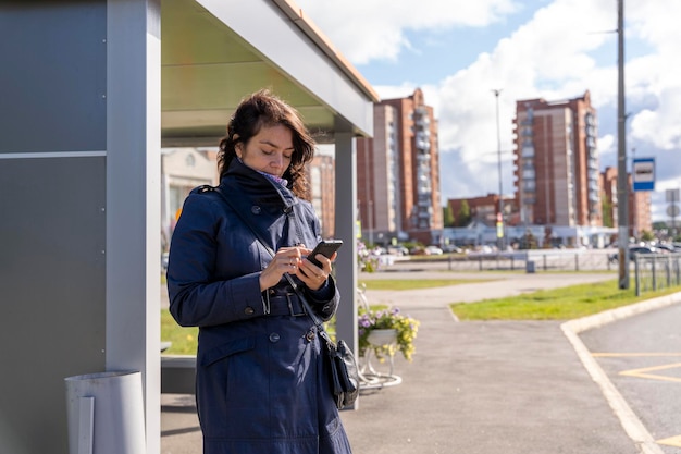 Woman reads information on a mobile phone while waiting for a bus