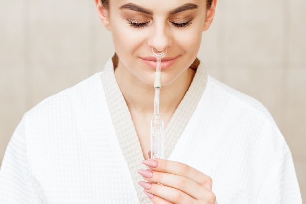 Woman receives nasal inhalation Maholda by essential oil in nose at spa.