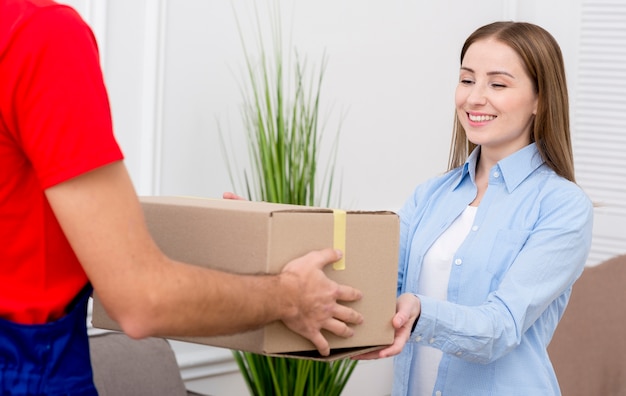 Woman receiving a cardboard box from courier