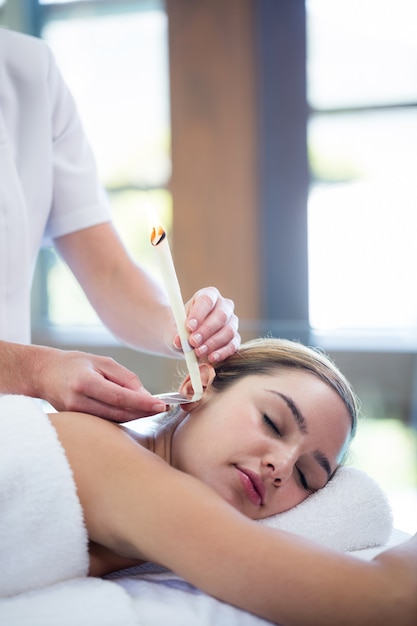 Woman receiving ear candle treatment